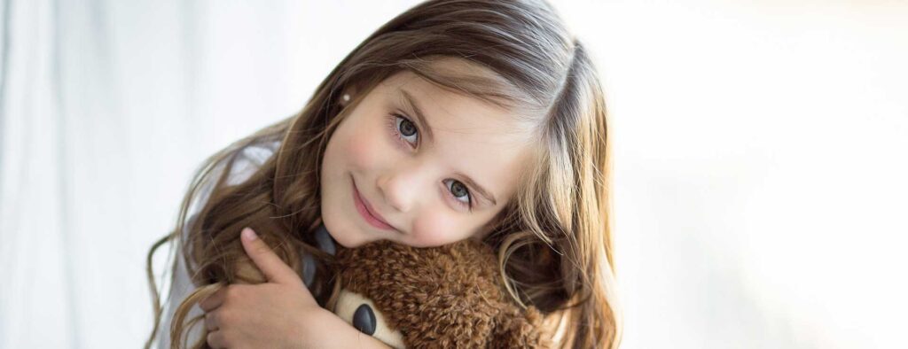 Young girl hugging a teddy bear.