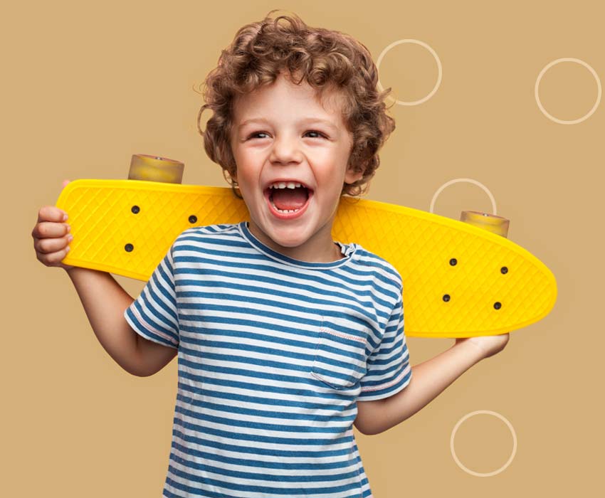 Smiling kid holding a skateboard.